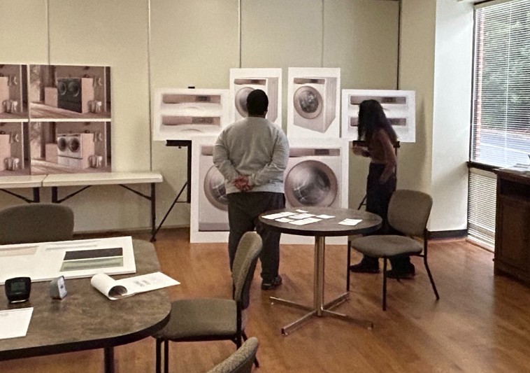 View through the observation window: Shreya moderates a participant reviewing washer and dryer design boards